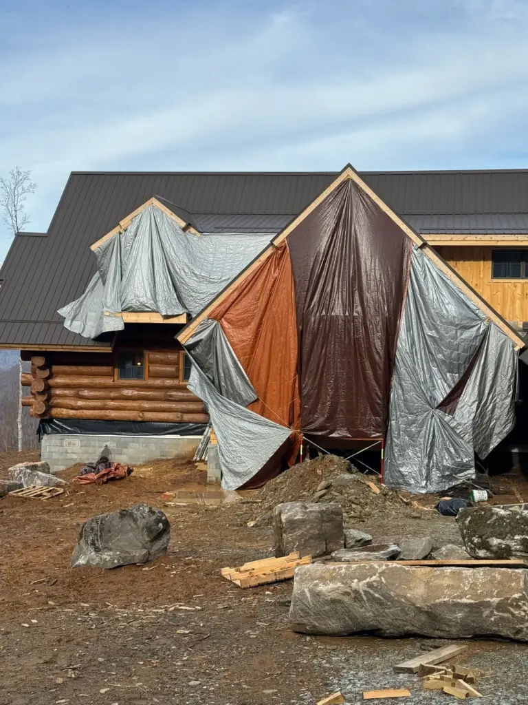 A log cabin covered in tarps during a remodel
